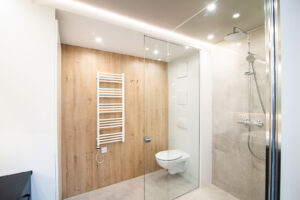 Bathroom with a wood-effect wall, a black vanity unit and a large backlit mirror.