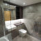 Grey bathroom with a bathtub behind a glass screen, a wall-hung toilet and a gold-accented niche.