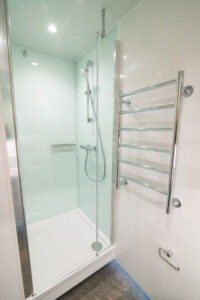 White bathroom with a glazed shower enclosure and a chrome towel radiator.