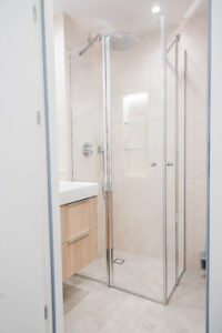 Bathroom with a shower enclosure, a wooden vanity and beige tiles.