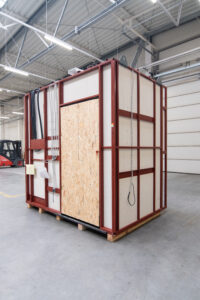 Prefabricated bathroom pod with an OSB door on a steel frame, in the production hall.
