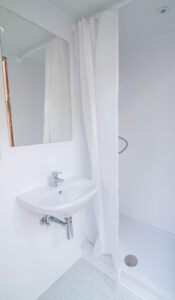 White bathroom with a basin, a mirror and a curtained shower.