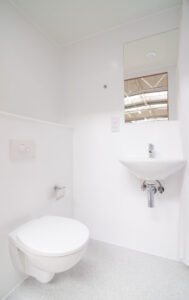 White bathroom with a wall-hung toilet, a basin and a window.