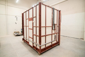 Prefabricated bathroom pod on a steel frame with white cladding, in the production hall.