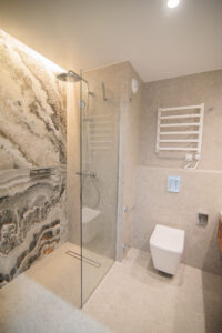 Bathroom with a decorative onyx feature wall, a walk-in shower, a wall-hung toilet and a white radiator.
