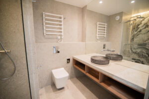 Bathroom with two countertop basins on a wooden top, a walk-in shower and a decorative stone wall.