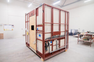 Prefabricated bathroom pod with an OSB door and installation routed beneath the floor.