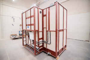 Prefabricated bathroom pod on a red frame with complete water and drainage installation.